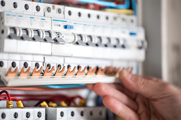 High-quality image of an electrician working on an electrical circuit breaker panel, showcasing professional electrical wiring and wiring safety, relevant to Perth electrical services.