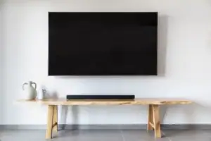 Modern living room with a flat-screen TV mounted on the wall and a natural wood console table, showcasing professional electrical installation by Westline Electricians Perth.